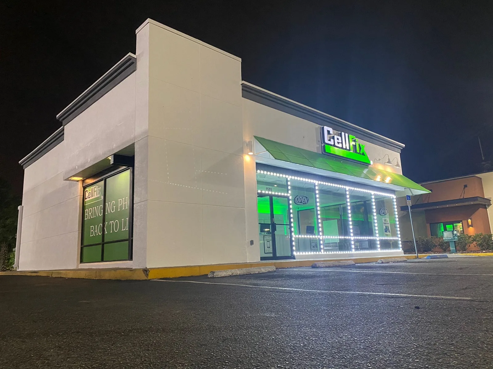 CellFix storefront at 1505 E Fowler Ave, Tampa — lit up at night with the green CellFix sign